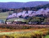 photo of steam locomotive traveling on tracks