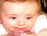 a baby sipping on a glass of water