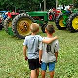 Two boys looking at a big green tractor at the Bedford Fair