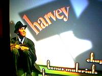 Jimmy Stewart sitting in front of a billboard of his famous movie Harvey