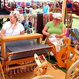 A photo of several rug makers working at their looms at the Kutztown Fesival