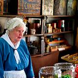 photo of a woman caring for the general store at Old Bedford Village Colonial Christmas event