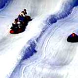 children snowtubing down a snowy slope