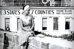 an old black and white photo of a young woman sitting in front of The U.S. Grand View Hotel